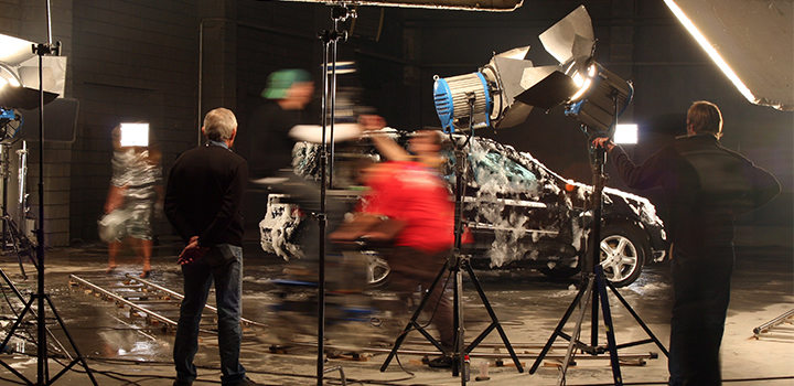 Blurred motion photo of producers filming a car on set.