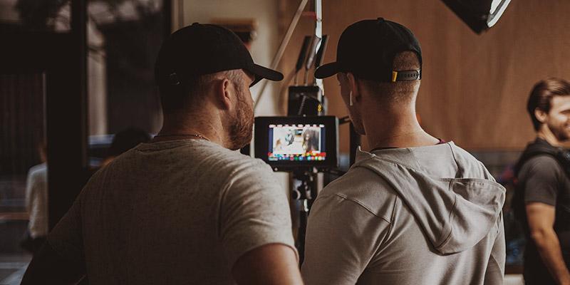 A digital imaging technician and a director of photography review footage on a small screen