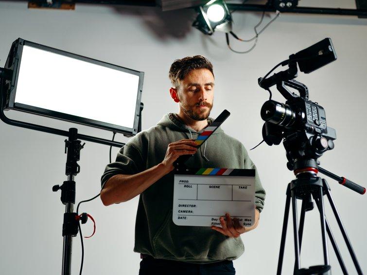 Bearded man holds clapperboard in film studio