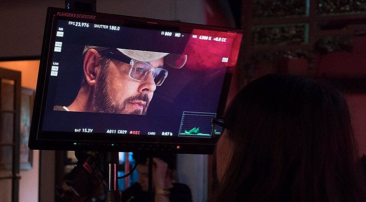 A person looking up at a video preview screen at a production set