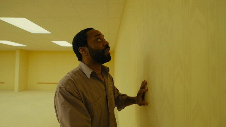 Chiwetel Ejiofor as Clark touching a yellow wall in Backrooms
