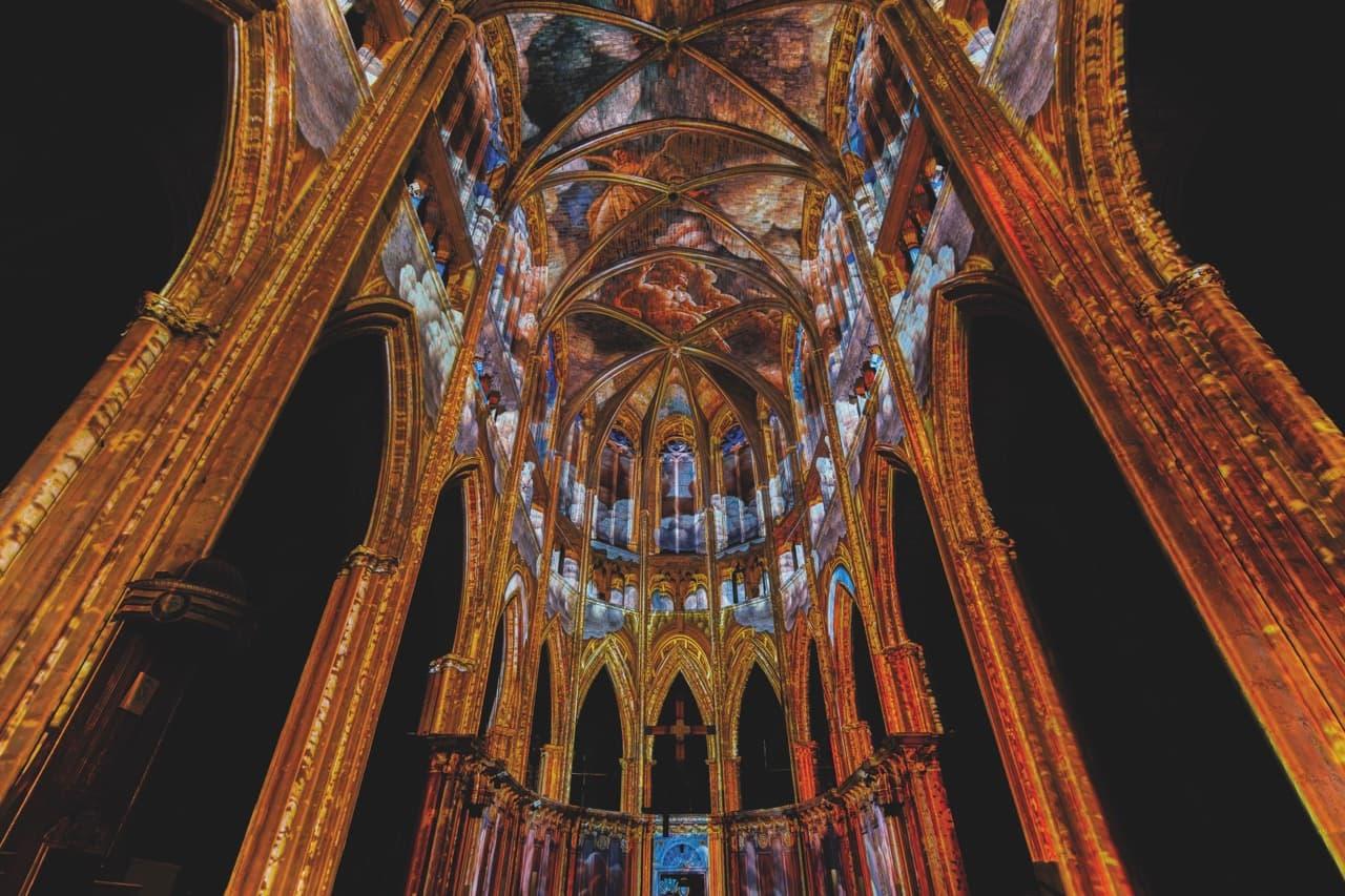 The roof of a cathedral with artwork projected onto the ornate ceiling